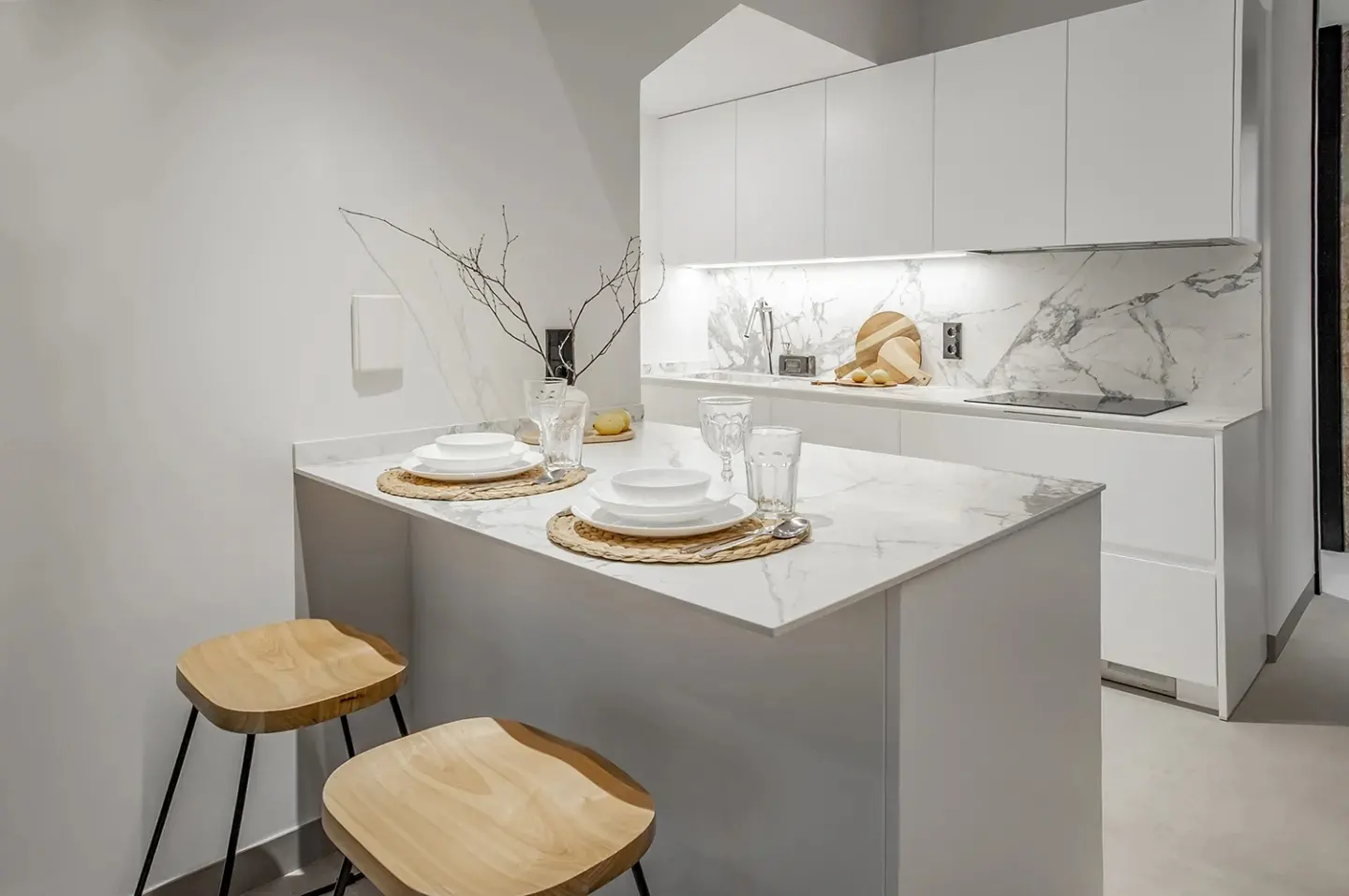 Isla con encimera de mármol y taburetes de madera en la nueva cocina