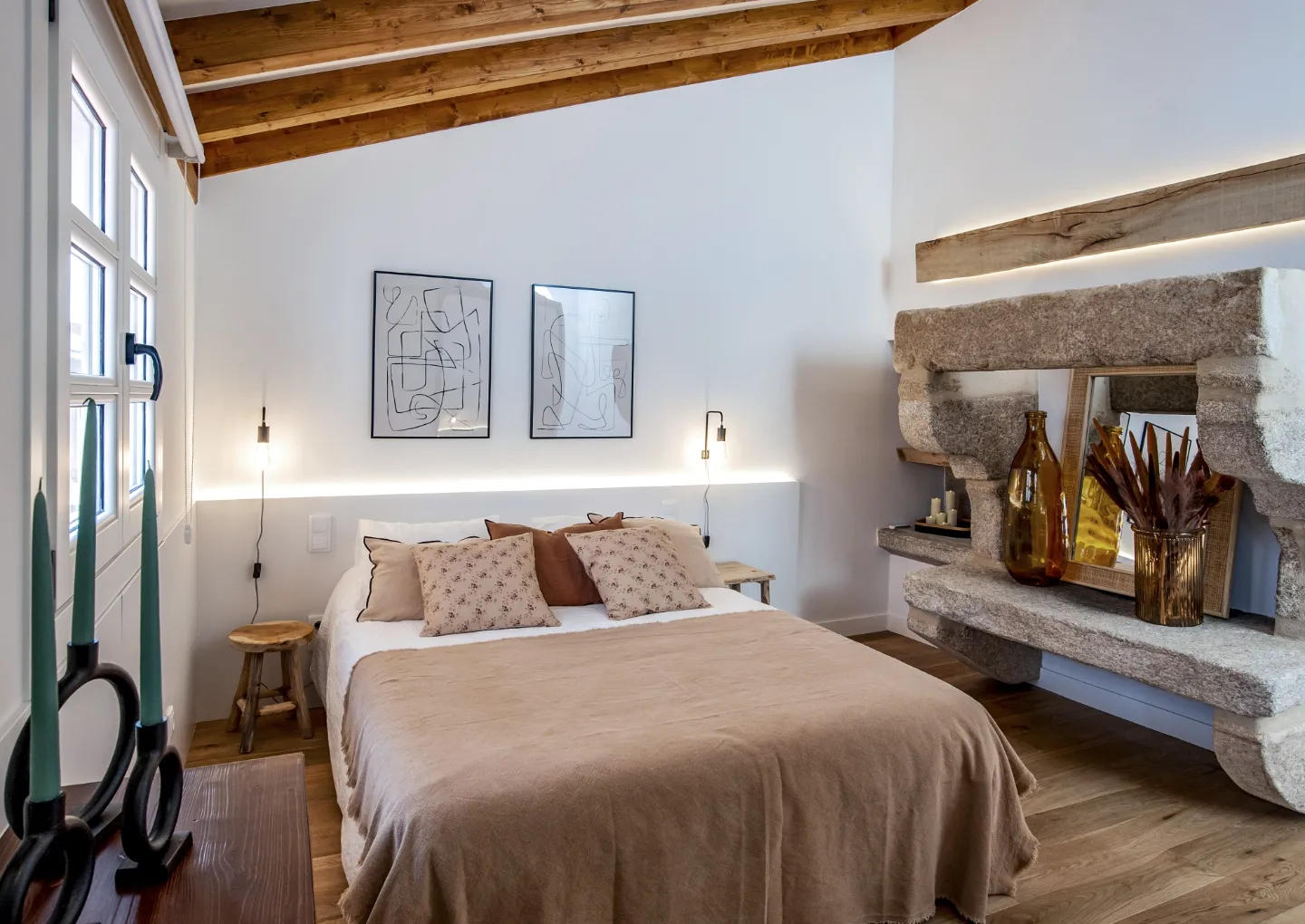El dormitorio abuhardillado, con vigas de madera y ventana de piedra retroiluminada