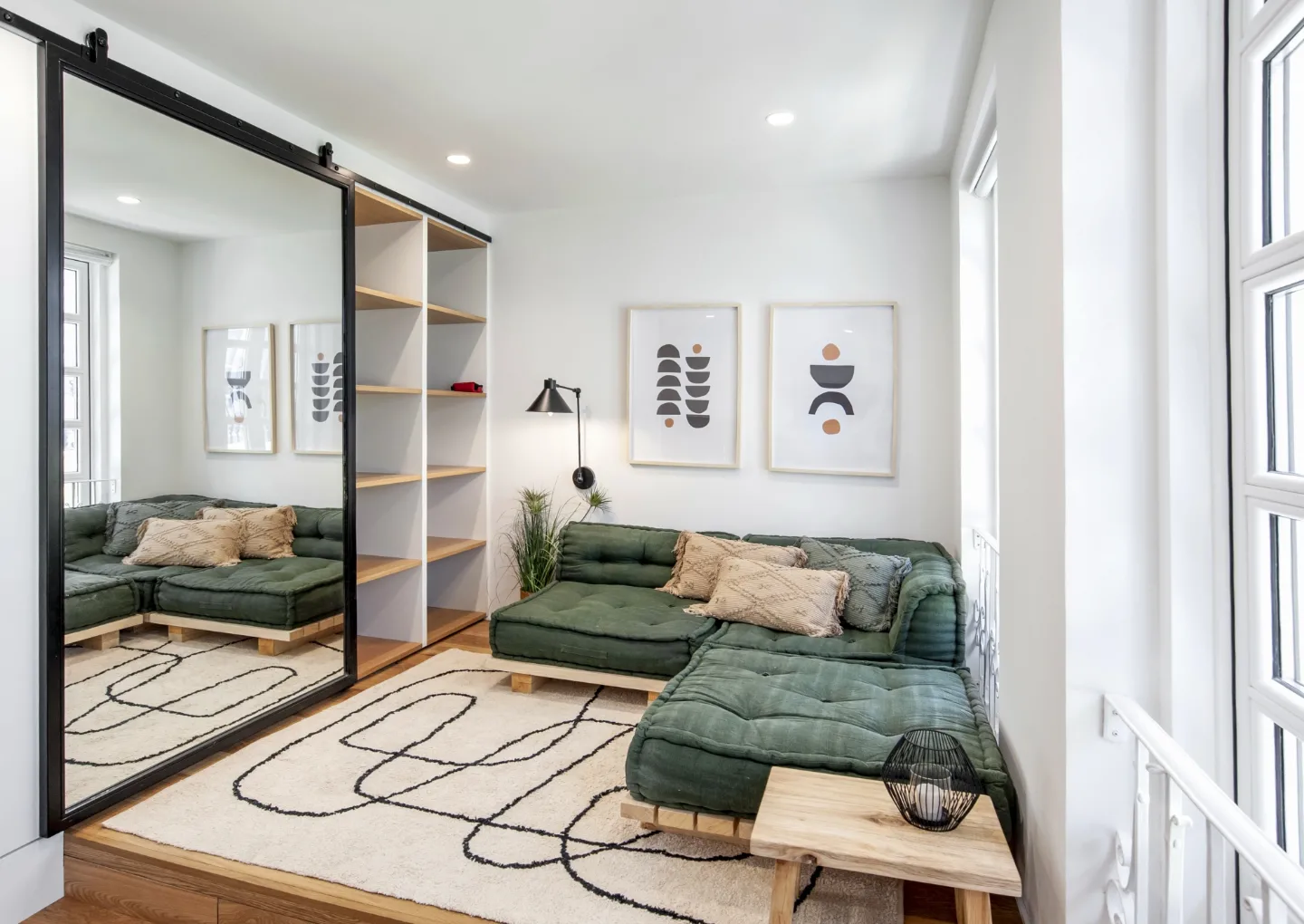La sala de estar, con sofá verde de suelo y gran espejo corredero