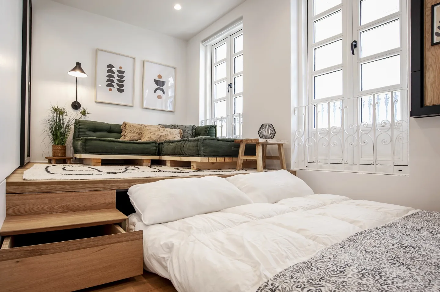 La tarima elevada del estar guarda una cama con cajones bajo la plataforma