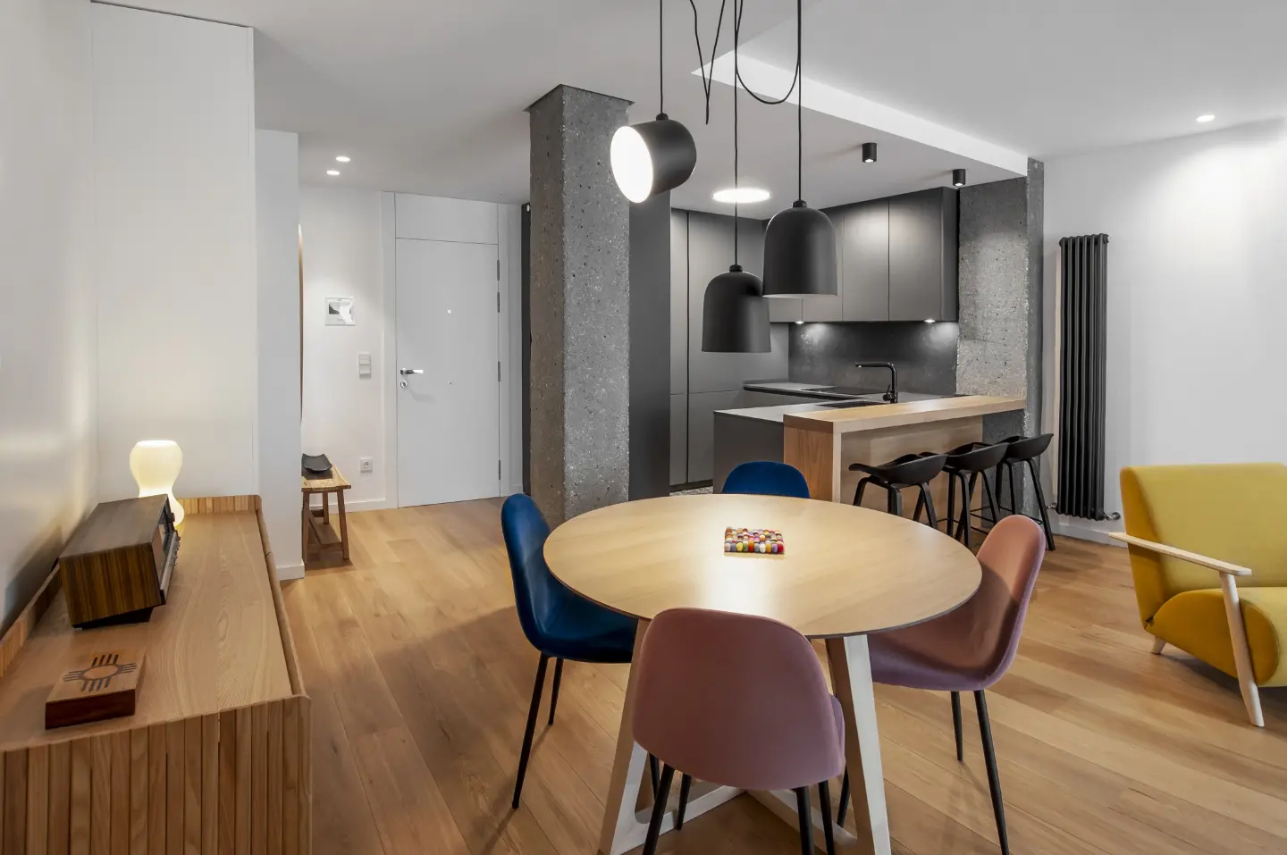 El comedor, con mesa redonda de roble, entre la cocina negra y el salón