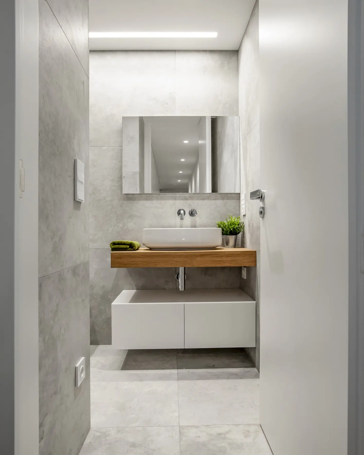 Baño en microcemento gris con lavabo sobre encimera de roble