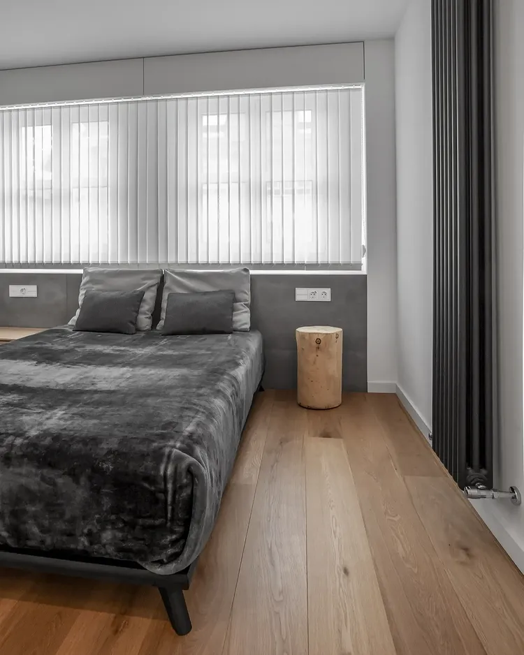 El dormitorio principal, en grises y roble, con un tronco de madera por mesilla