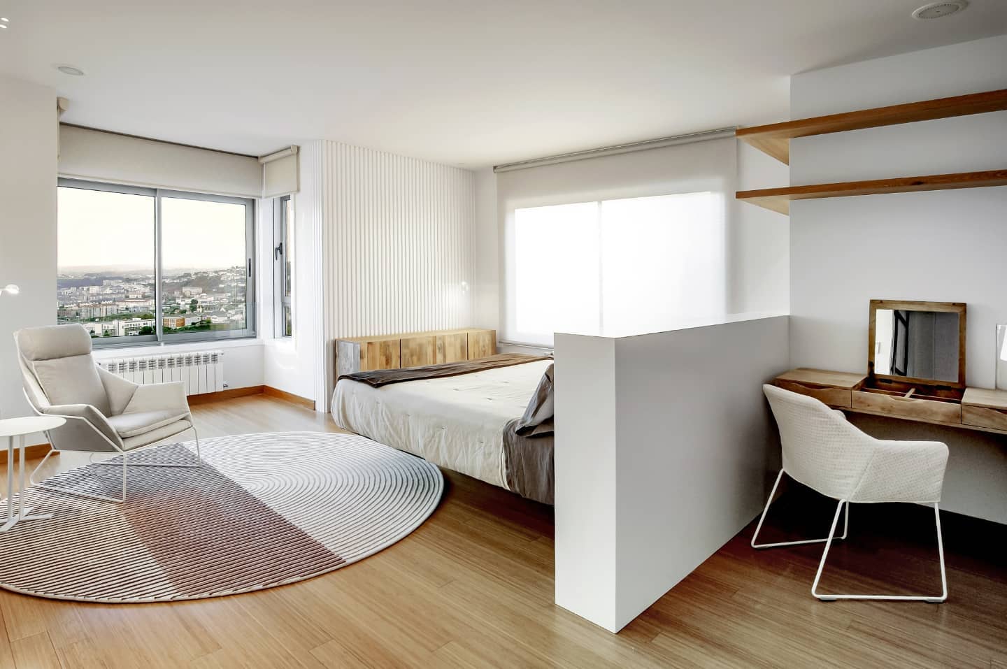 El dormitorio principal, con tocador de madera tras el murete y vistas a la ciudad