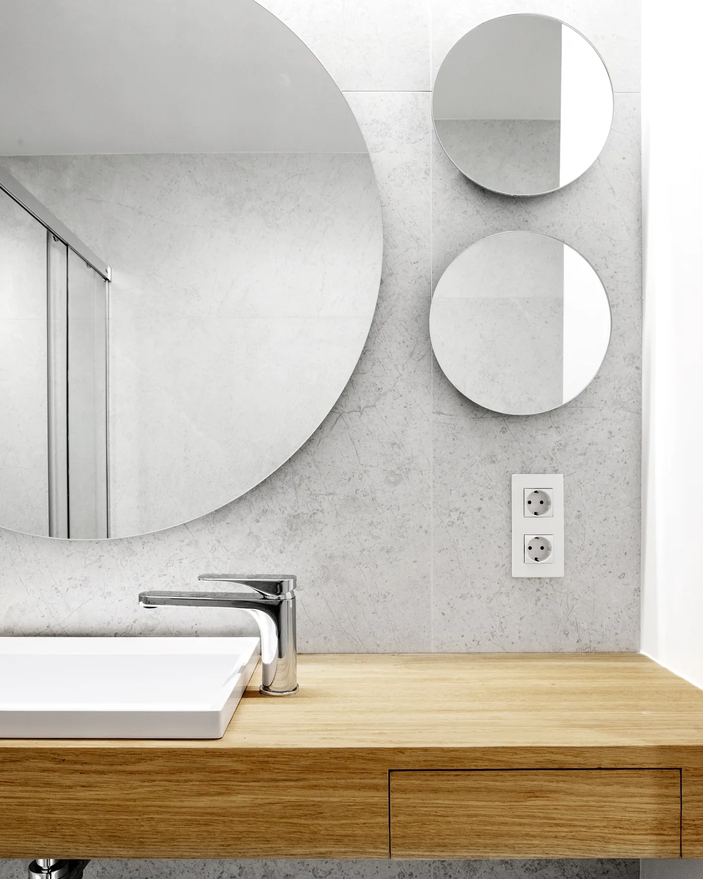 Espejos redondos sobre la encimera de roble del segundo baño